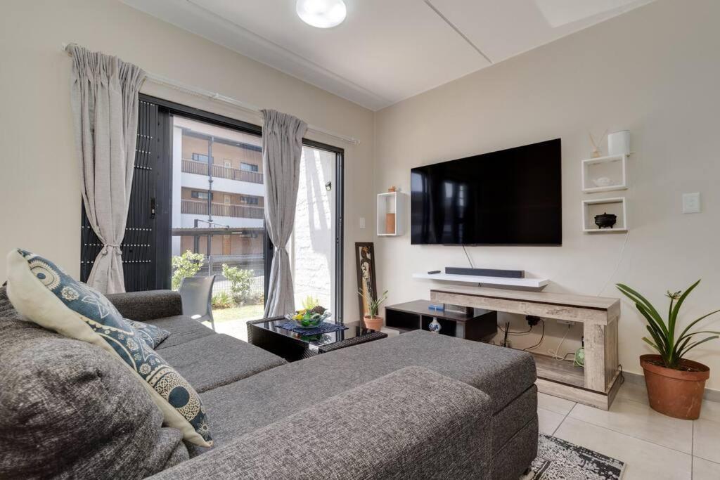 Una sala de estar con un sofá y un televisor de pantalla plana. en GroundEazy beside Mall of Africa, en Midrand
