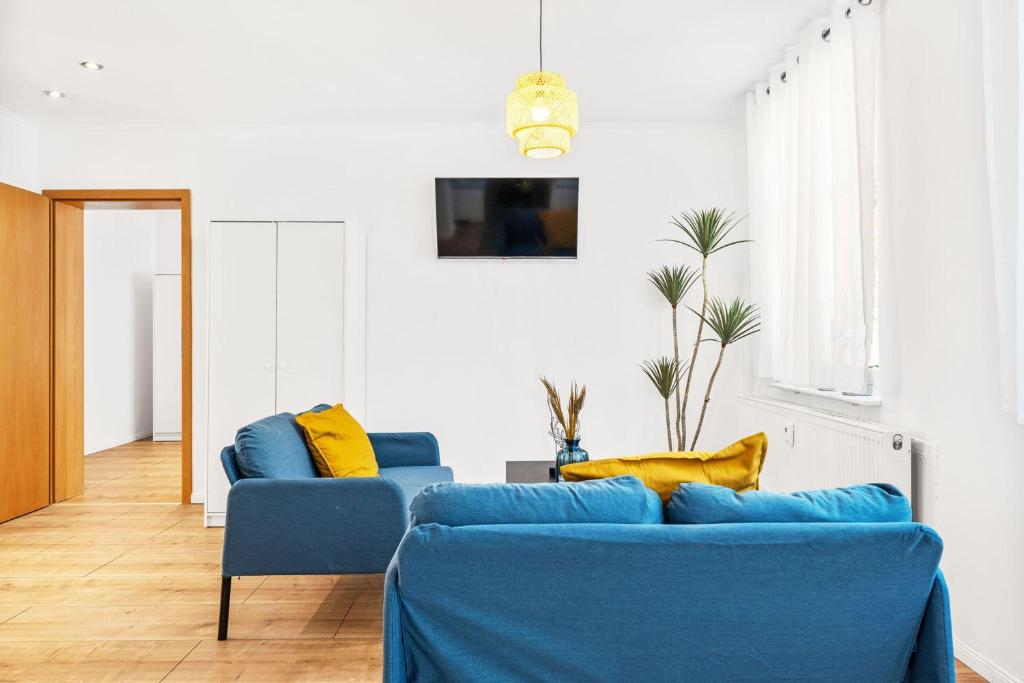 uma sala de estar com sofás azuis e almofadas amarelas em Chic & Modern Apartment em Jüterbog