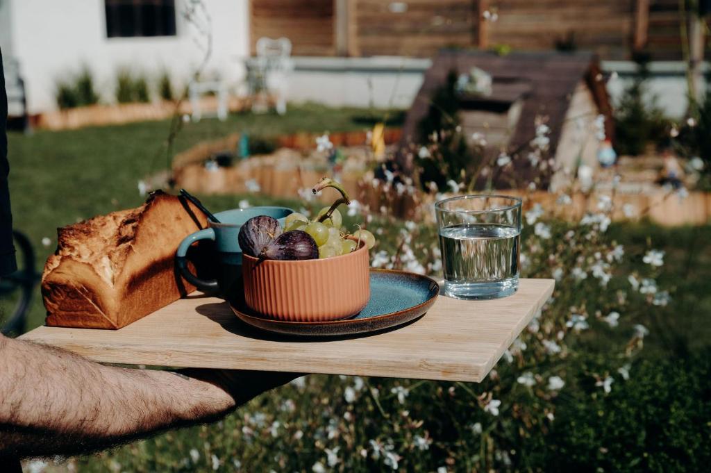 a person holding a table with a bowl of fruit and a glass at La Villa d'Hélène 2 - Chambres d'hôtes BnB et Appartements - Cluses in Cluses