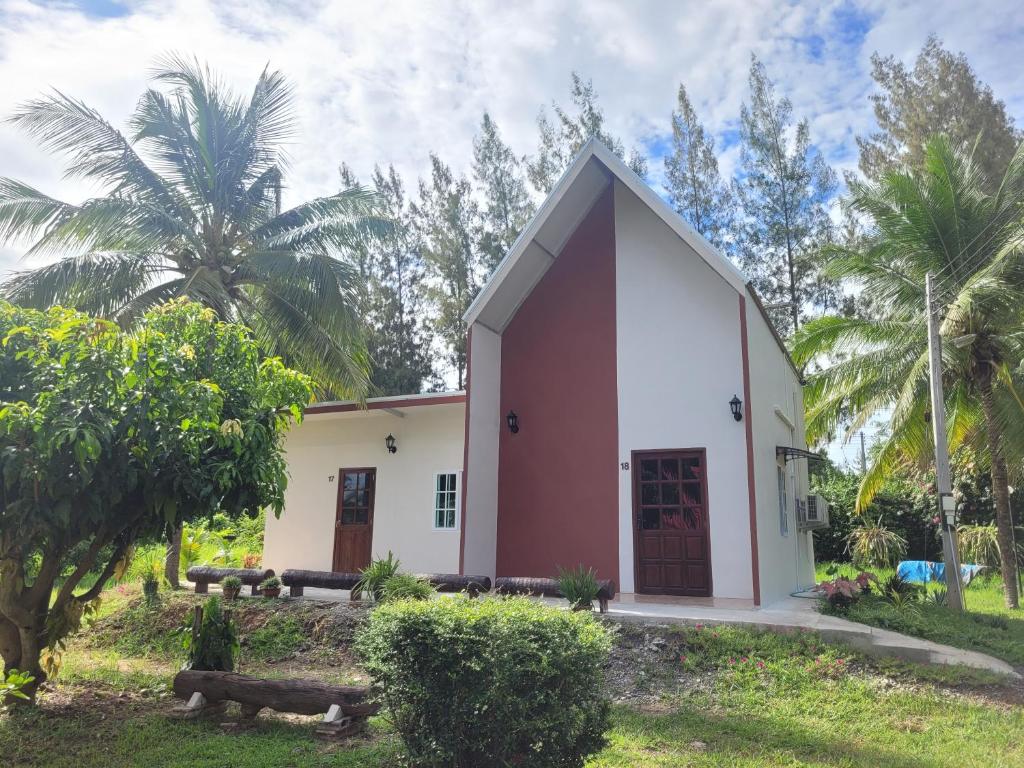 a small white and red building with palm trees at Sawan Srang Nang Kaew in Takhop