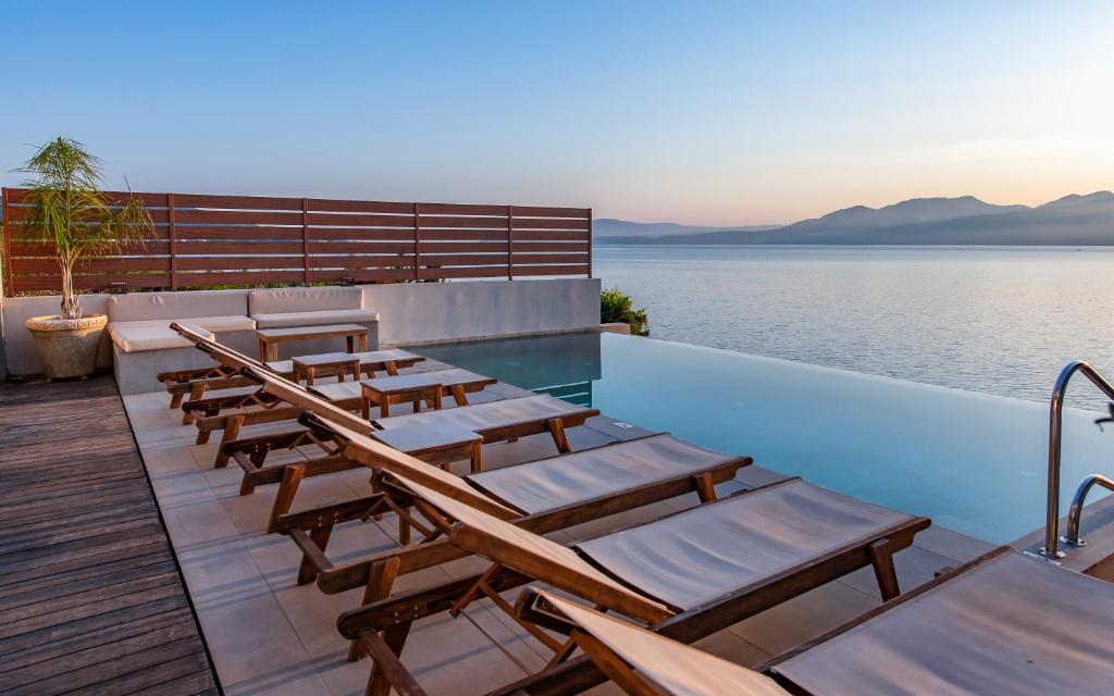 a row of chairs sitting on a deck next to the water at Nikiana Luxury Villas in Nikiana