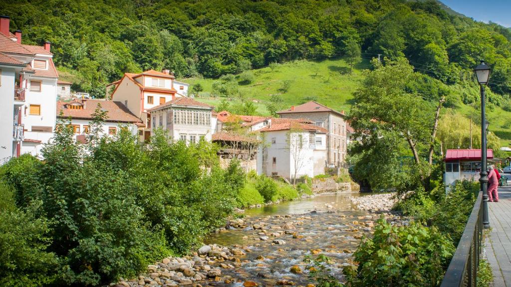 un río en una ciudad con edificios junto a una montaña en Alojamiento Calzada Romana, en Belmonte de Miranda