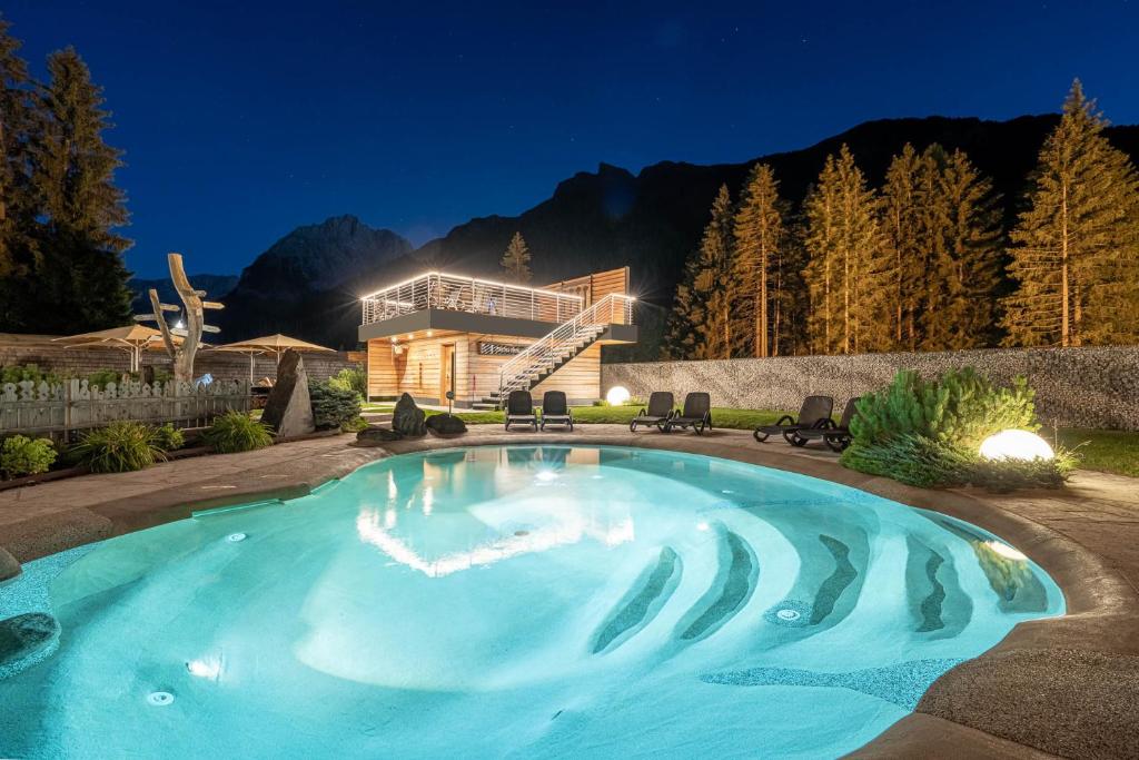una piscina di fronte a una casa di notte di Croce Bianca Leisure & Spa Hotel a Canazei