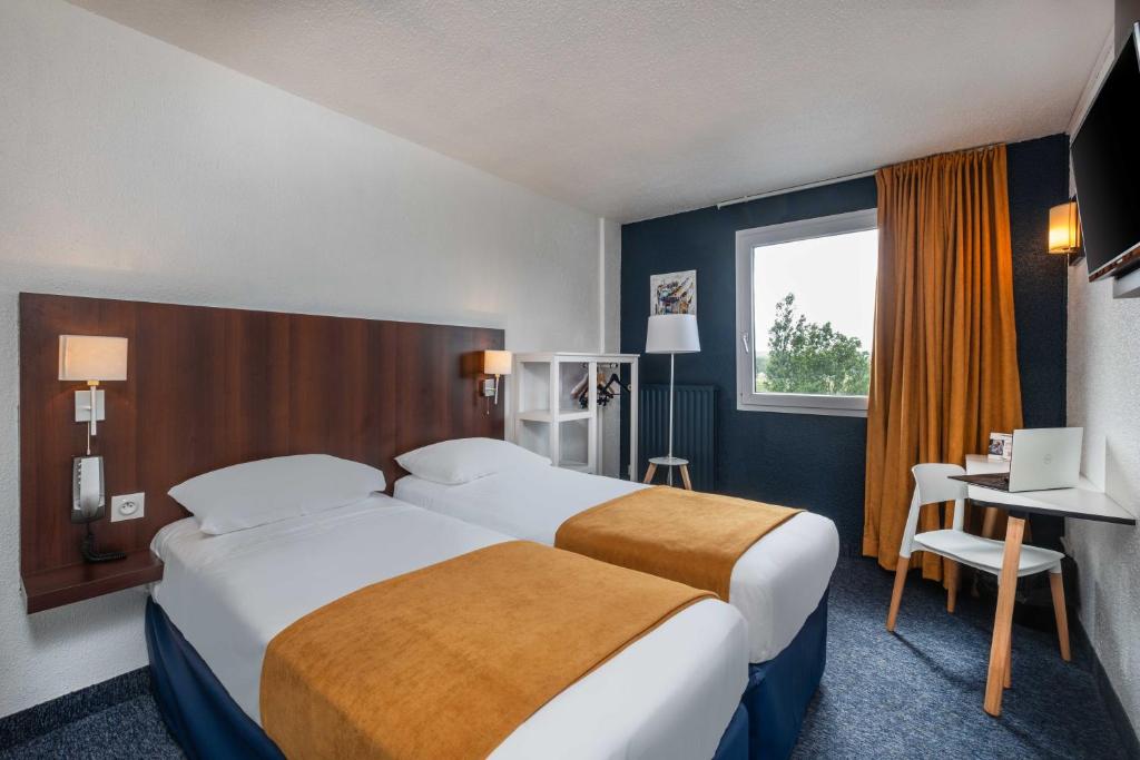 トゥールーズにあるThe Originals City, Hotel Ariane, Toulouseのベッド2台、デスク、窓が備わるホテルルームです。