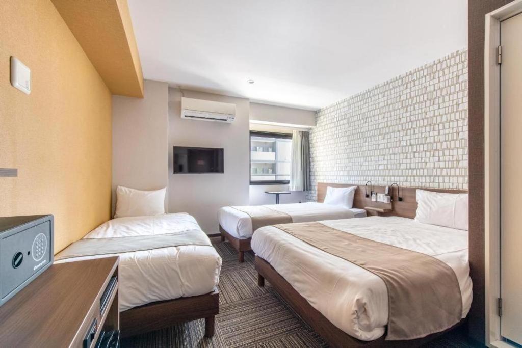 ein Hotelzimmer mit zwei Betten und einem Fernseher in der Unterkunft Hotel Sanrriot Osaka honmachi - Vacation STAY 22302v in Osaka