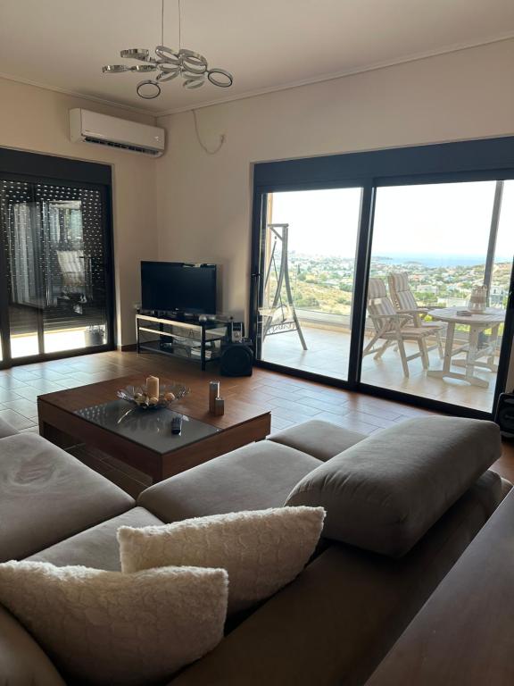 a living room with a couch and a large window at Villa Katerina in Kalívia Thorikoú