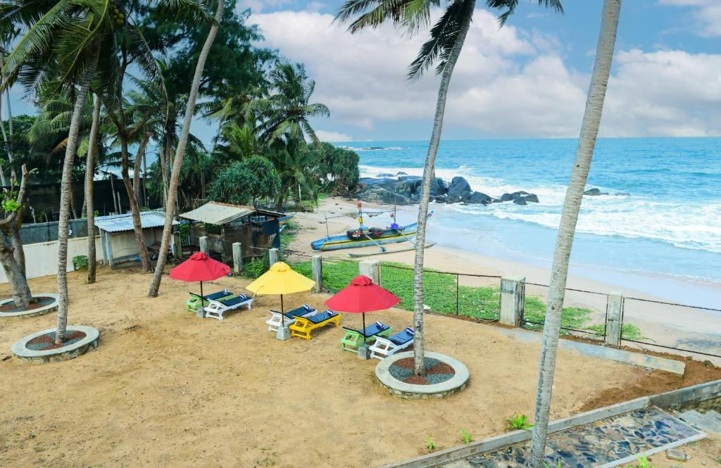 a beach with chairs and umbrellas and the ocean at Samudra Villa in Ambalangoda