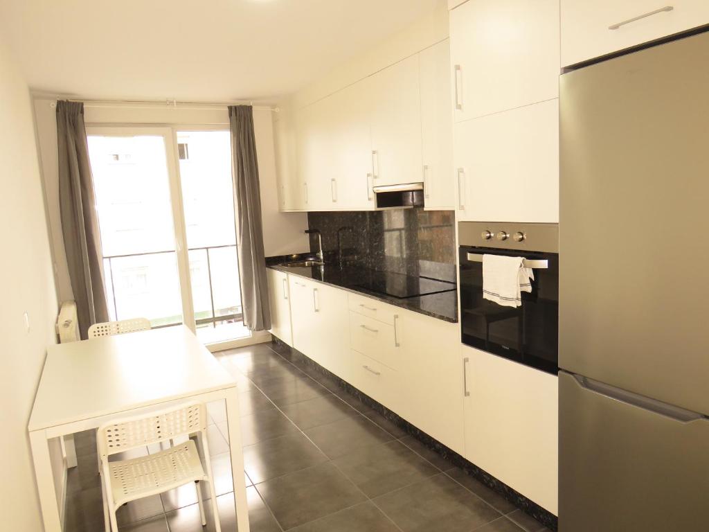 una cocina con armarios blancos y electrodomésticos negros en Rua ILLA PANCHA VIVIENDAS USO TURISTICO, en Ribadeo