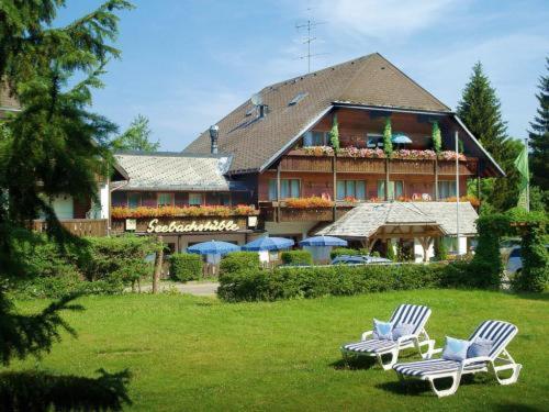 two lawn chairs in front of a large house at Hotel Garni Seebachstüble in Titisee-Neustadt