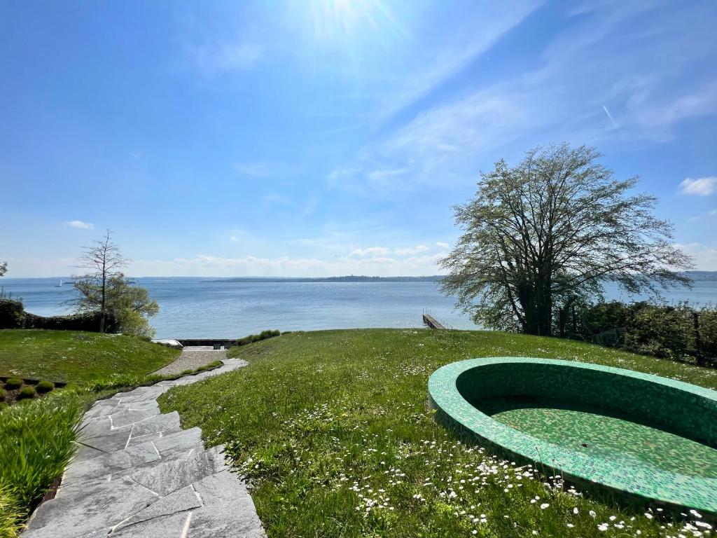 einem grünen Schlauch auf einem Grashügel neben dem Wasser in der Unterkunft Villa am See mit privatem Seezugang in Meersburg