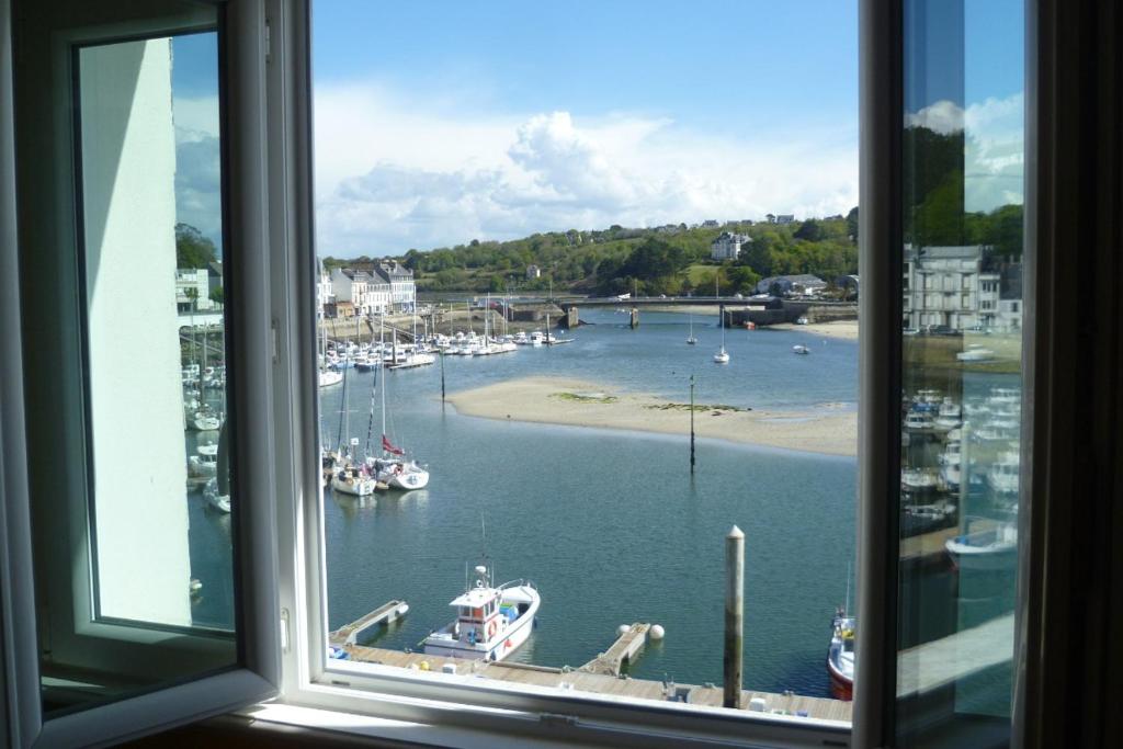 une fenêtre donnant sur un port de plaisance avec des bateaux dans l'eau dans l'établissement Mer de Vent, à Audierne