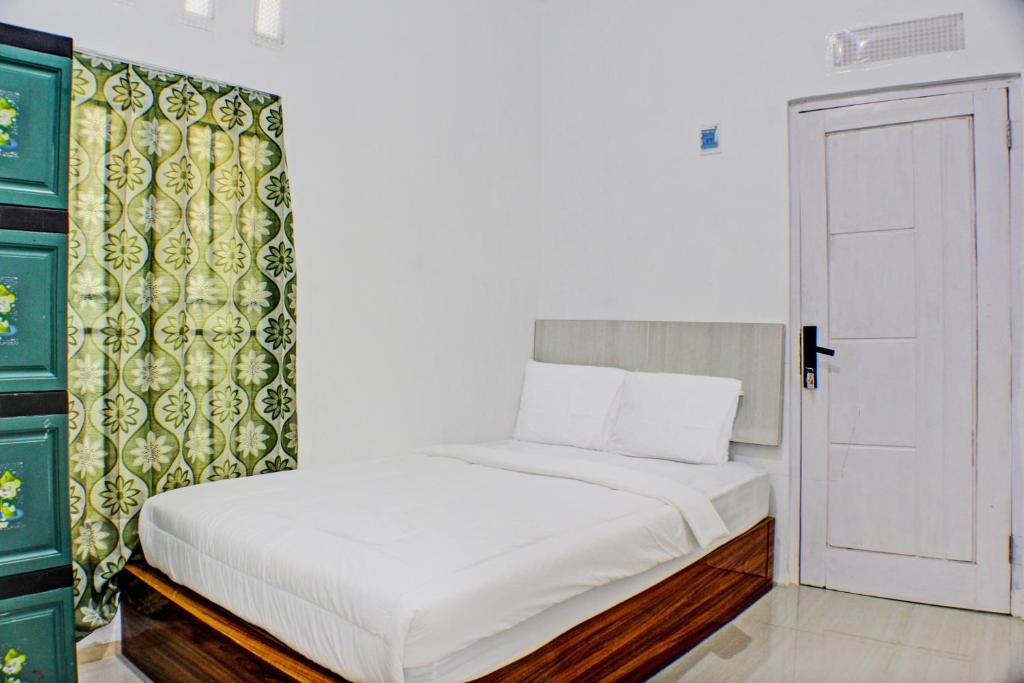 - une chambre avec un lit blanc et une porte dans l'établissement OYO Life 93138 Anugrah Kost Syariah, à Bandar Lampung