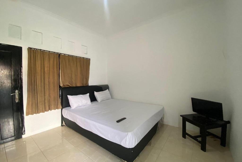 een slaapkamer met een bed met een laptop erop bij OYO Life 93156 Rumah Kosan in Tanjung