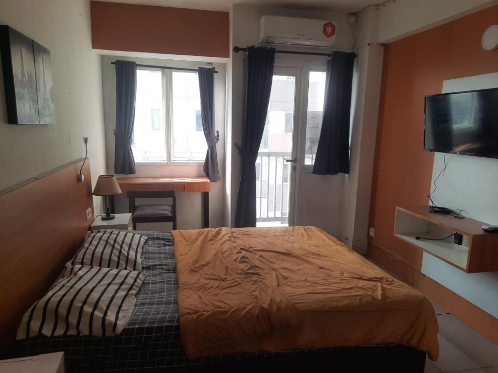 Schlafzimmer mit einem Bett, einem Schreibtisch und Fenstern in der Unterkunft OYO Life 93140 Apartment Grand Sentraland By Fahri in Jaken 1