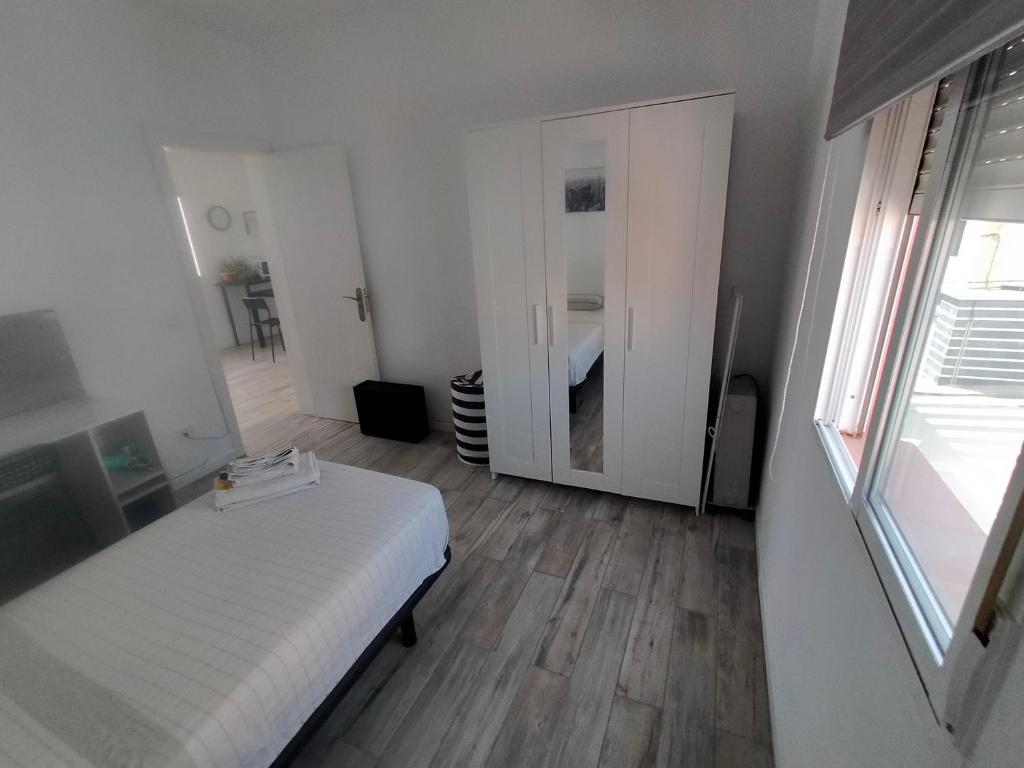 a small white bedroom with a bed and a mirror at Urban room in La Laguna