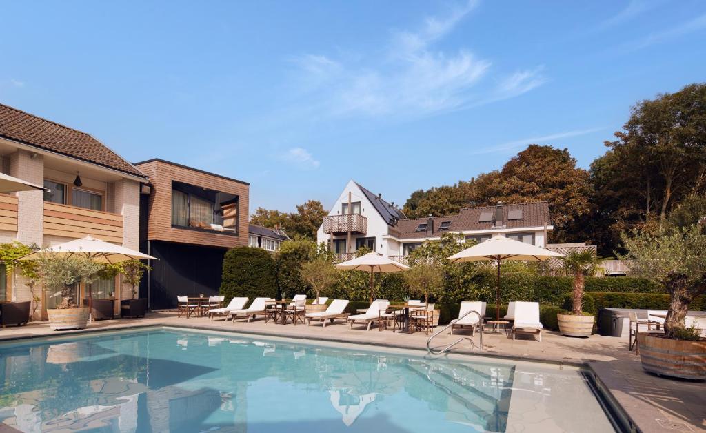 a swimming pool with chairs and umbrellas next to a house at Villa Noordzee in Renesse