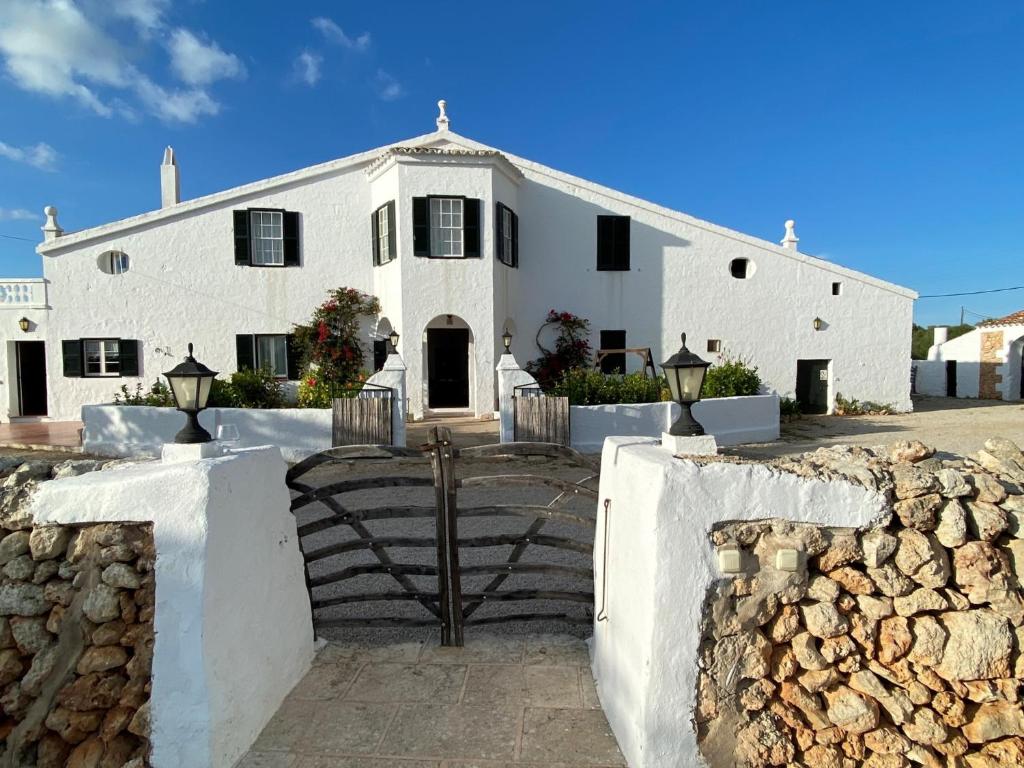 une maison blanche avec une clôture en pierre devant elle dans l'établissement Holiday Home Finca SANT JAUME, à Alaior