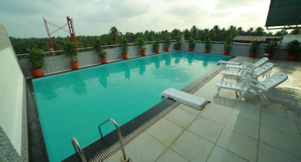 a large swimming pool with a bunch of chairs in it at Nakshatra Emerald in Guruvāyūr