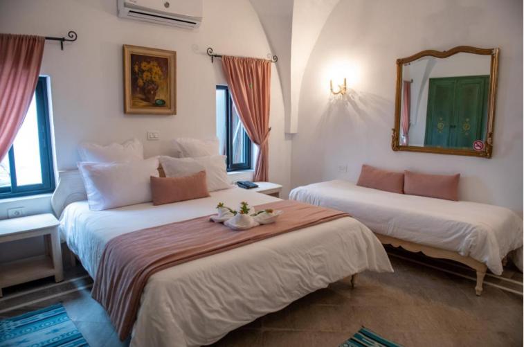 una camera d'albergo con due letti e uno specchio di Dar Gino a Kelibia