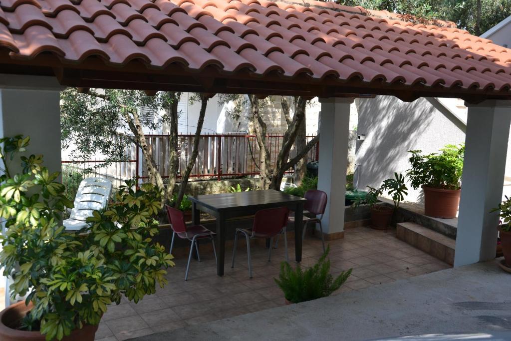 un patio con mesa y sillas bajo un techo en Apartmani Dub, en Cavtat