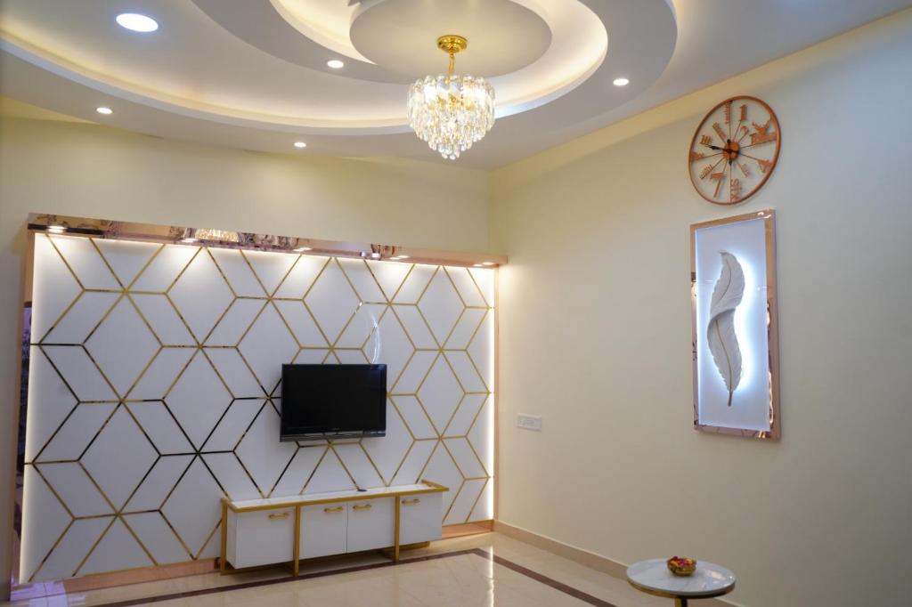 a living room with a tv on a wall and a clock at Visalam service apartment in Chennai