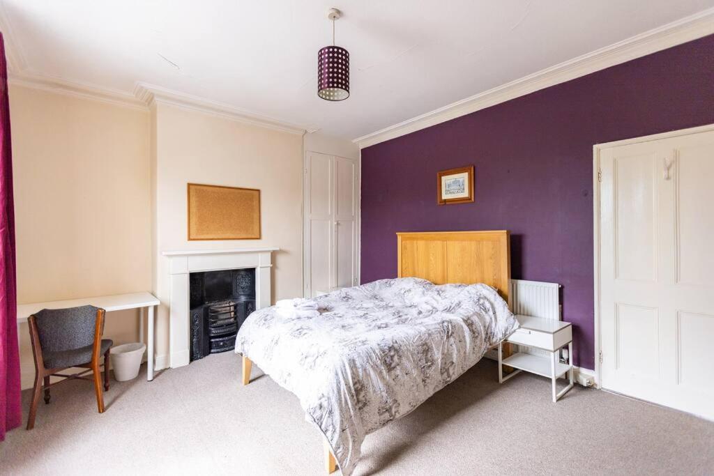 um quarto com uma cama e uma parede roxa em Park View House - Sleeps 6 em York