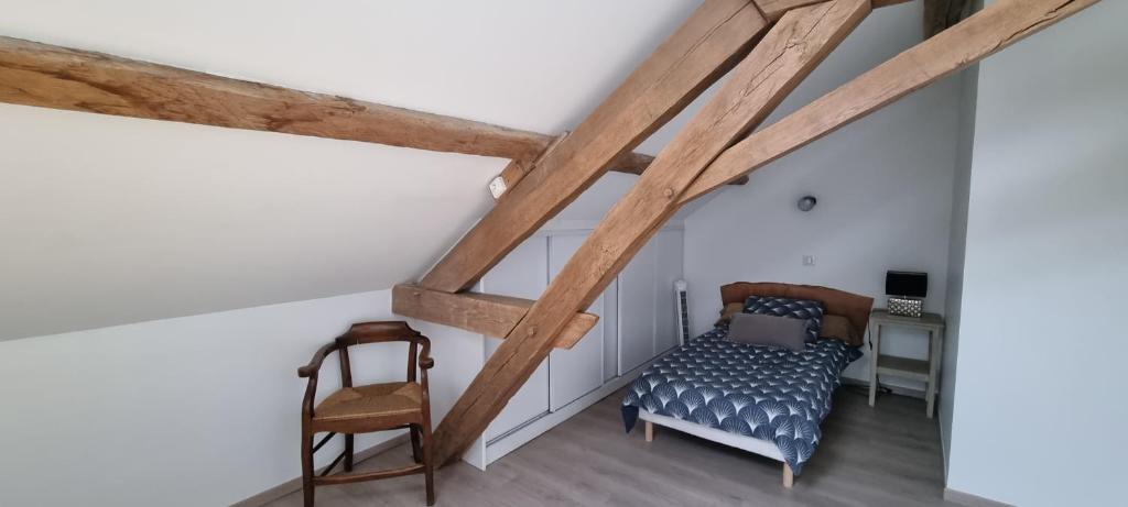 a attic bedroom with a bed and a chair at Meublé de tourisme &quot;Les brosses tillots&quot; in Mary