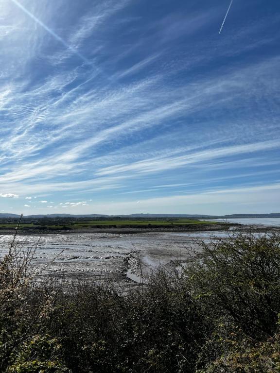 a beach with water and a blue sky and clouds at Garden Place in Clevedon