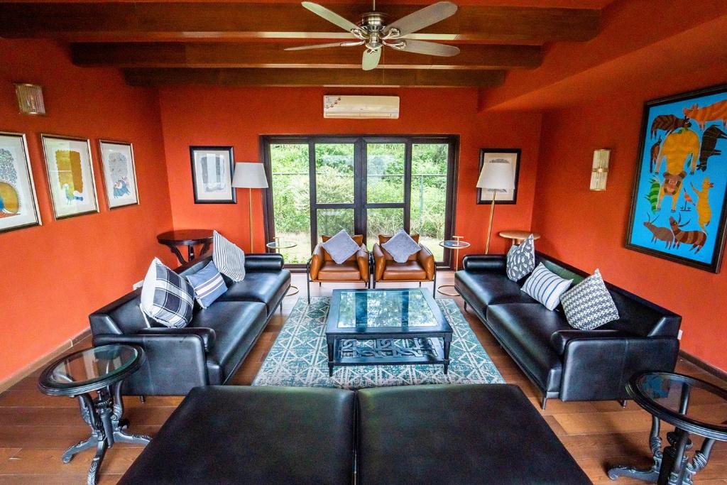 uma sala de estar com paredes cor de laranja e mobiliário em couro preto em villa 1314 em Kasauli
