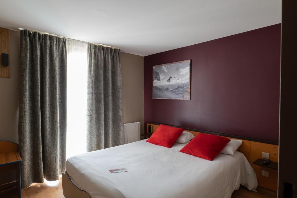 a bedroom with a bed with two red pillows at Hôtel Les Arches in Saint-Lary-Soulan