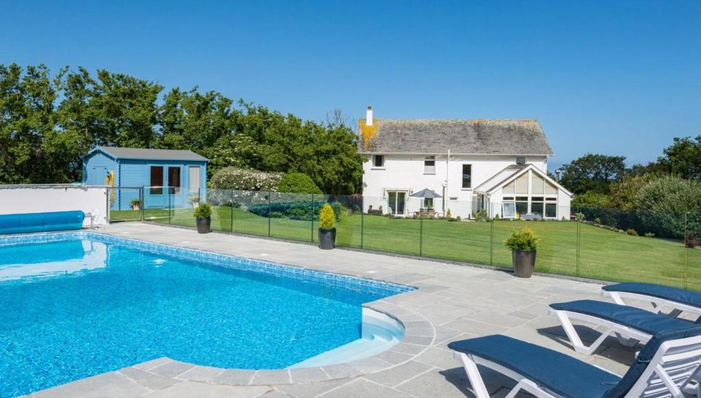 a swimming pool with chairs and a house in the background at Beautiful 5-Bed House in Port Isaac in Port Isaac