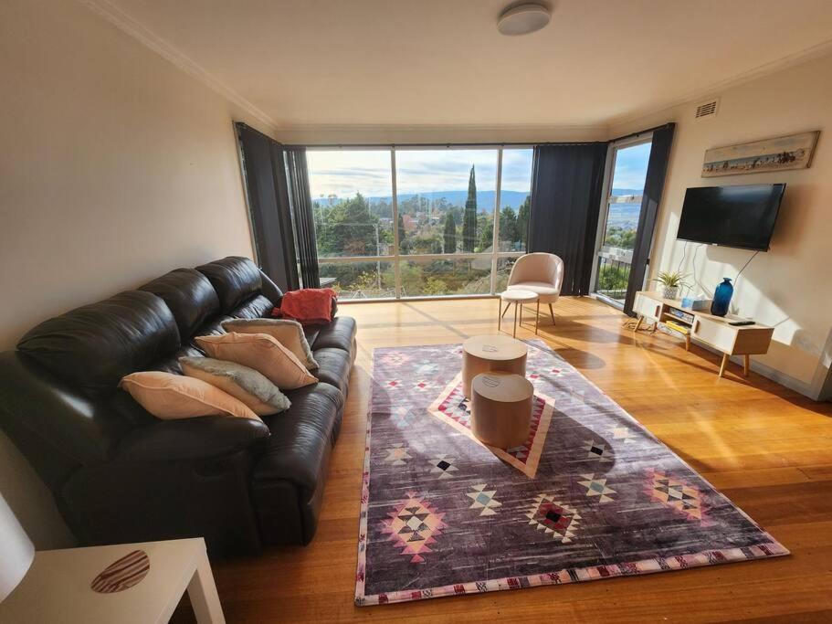 uma sala de estar com um sofá de couro e uma grande janela em Holiday house at Trevallyn em Royal Park