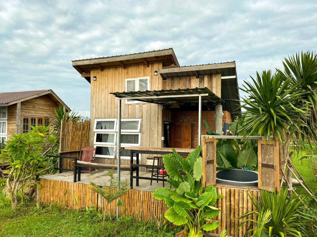 Casa de madera con mesa y patio en Dee Tor Jai Farm Stay ดีต่อใจฟาร์มสเตย์ en Chiang Klang
