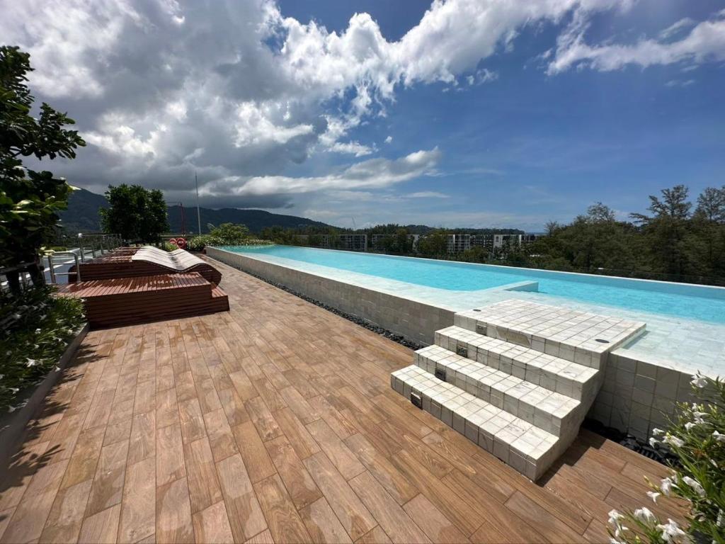 a swimming pool with benches next to a wooden deck at Apartments in Skypark Laguna Bang Tao in Bang Tao Beach
