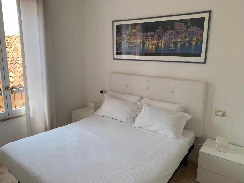 białe łóżko z białymi poduszkami i zdjęciem na ścianie w obiekcie Garibaldi18 w mieście Desenzano del Garda