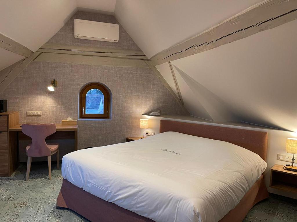a bedroom with a bed and a desk and a window at Hôtel Restaurant La Charrue in Sand