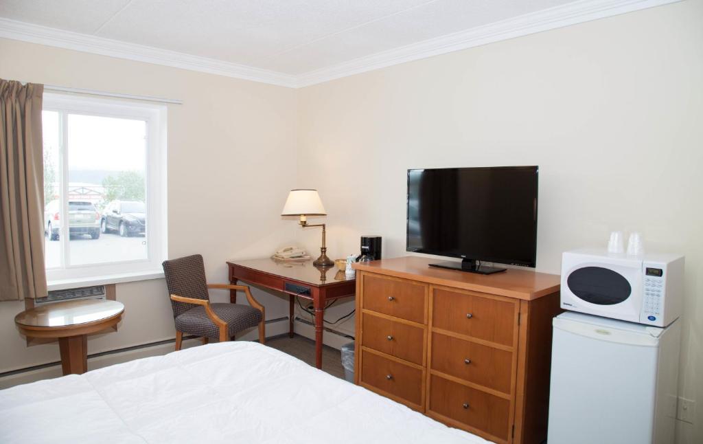 a hotel room with a bed and a tv and a desk at Twin Pine Inn & Suites in Hinton