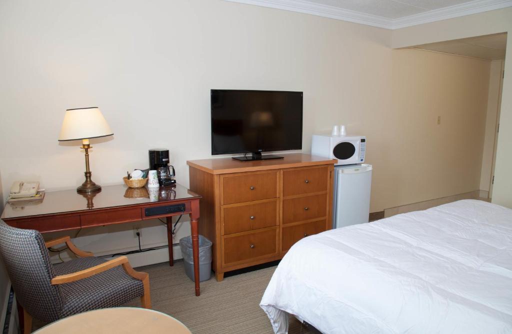 a bedroom with a bed and a desk with a television at Twin Pine Inn & Suites in Hinton