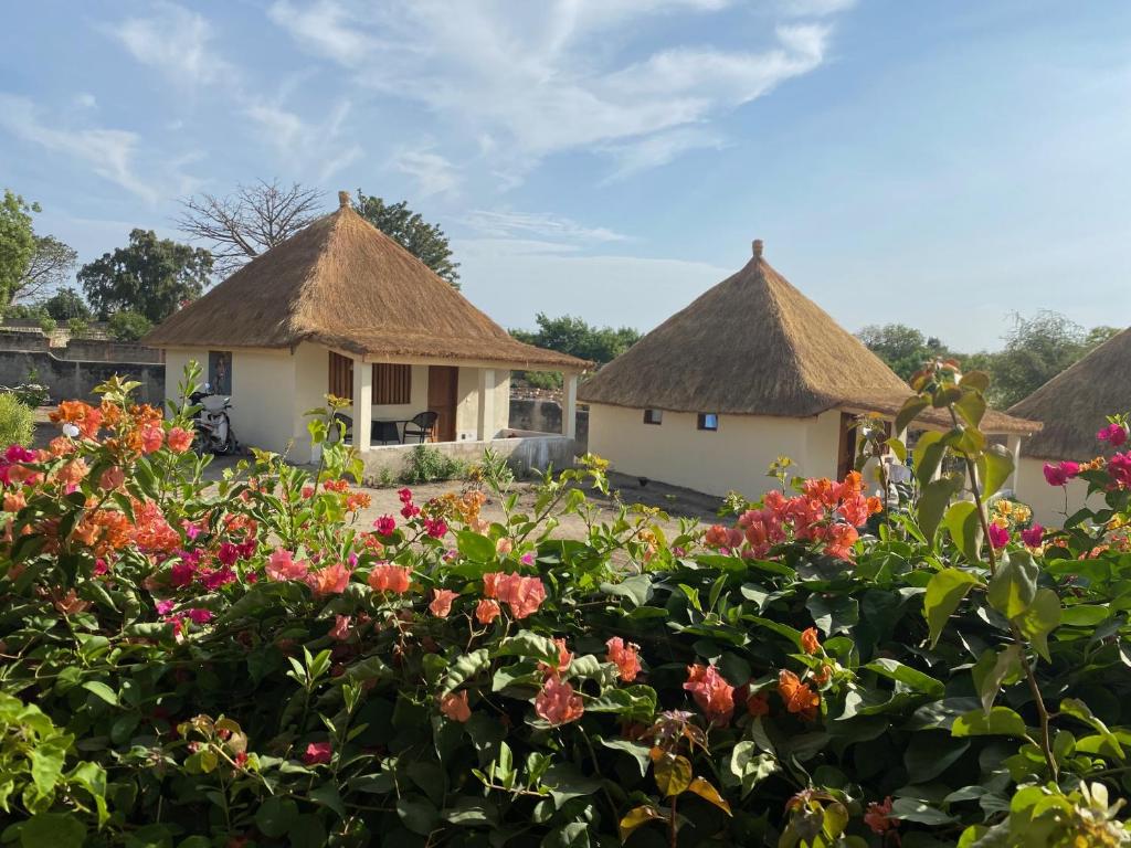 a group of huts with flowers in the foreground at Toubacouta Lodges in Toubakouta