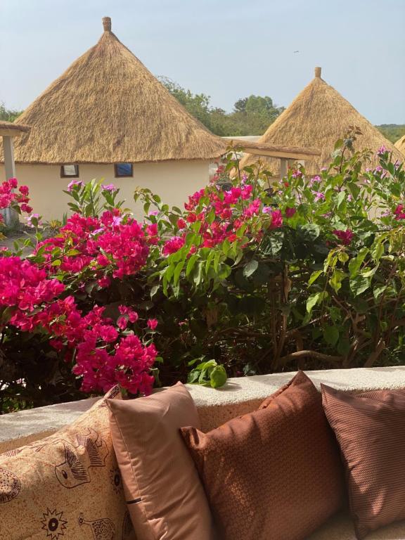 a couch in front of pink flowers and huts at Toubacouta Lodges in Toubakouta