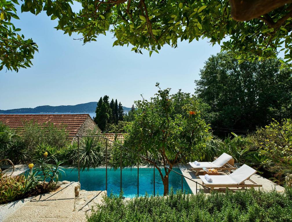 - une piscine avec 2 chaises longues à côté de la piscine dans l'établissement Villa Lemonia, à Trsteno