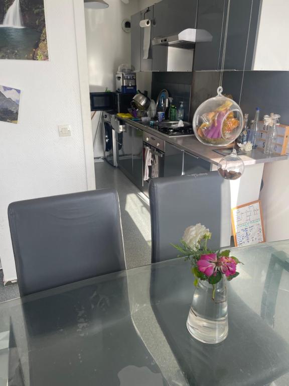 une cuisine avec une table en verre et un vase de fleurs dans l'établissement appart lumineux à 9m de Paris JO, à Villejuif