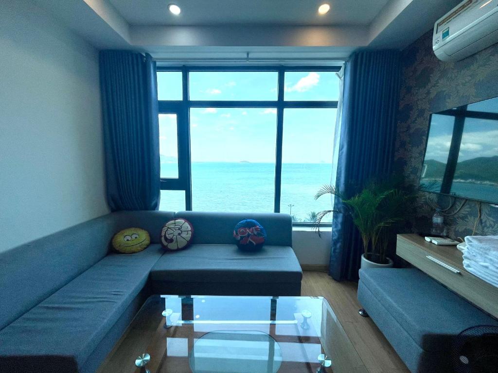a living room with a blue couch with a view of the ocean at Mường Thanh Luxury Viễn Triều Apartment in Nha Trang