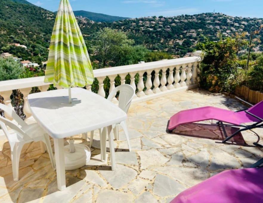 una mesa blanca y sillas en un patio con vistas en CAVALOC T2 terrasse vue colline en Cavalaire-sur-Mer