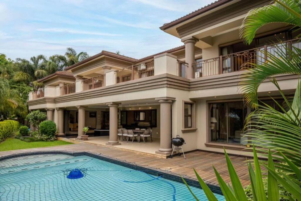 a house with a swimming pool in front of it at Palms On Byrne: Where Elegance Meets Serenity in Durban
