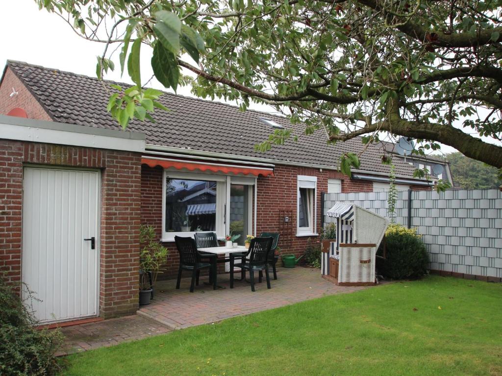 Casa de ladrillo con patio con mesa y sillas en Bungalow in Berumbur nahe Norddeich Strand, en Berumbur