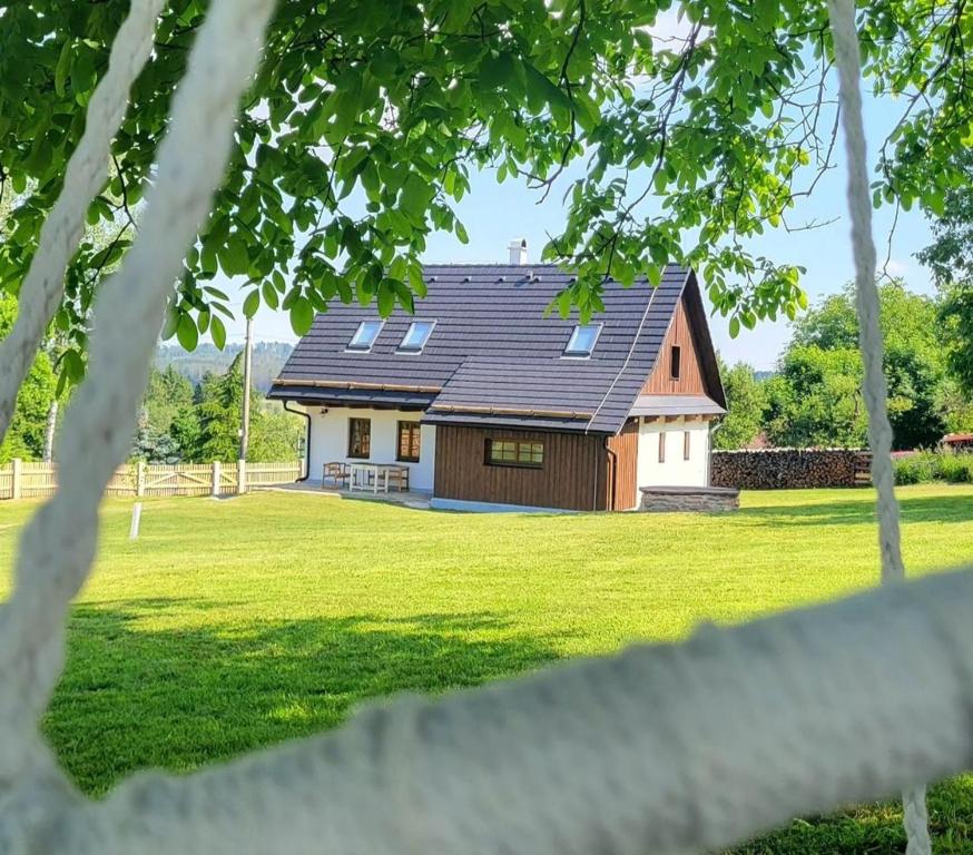 a house with a black roof on a green field at Chaloupka Pomněnka na Lipce in Nasavrky