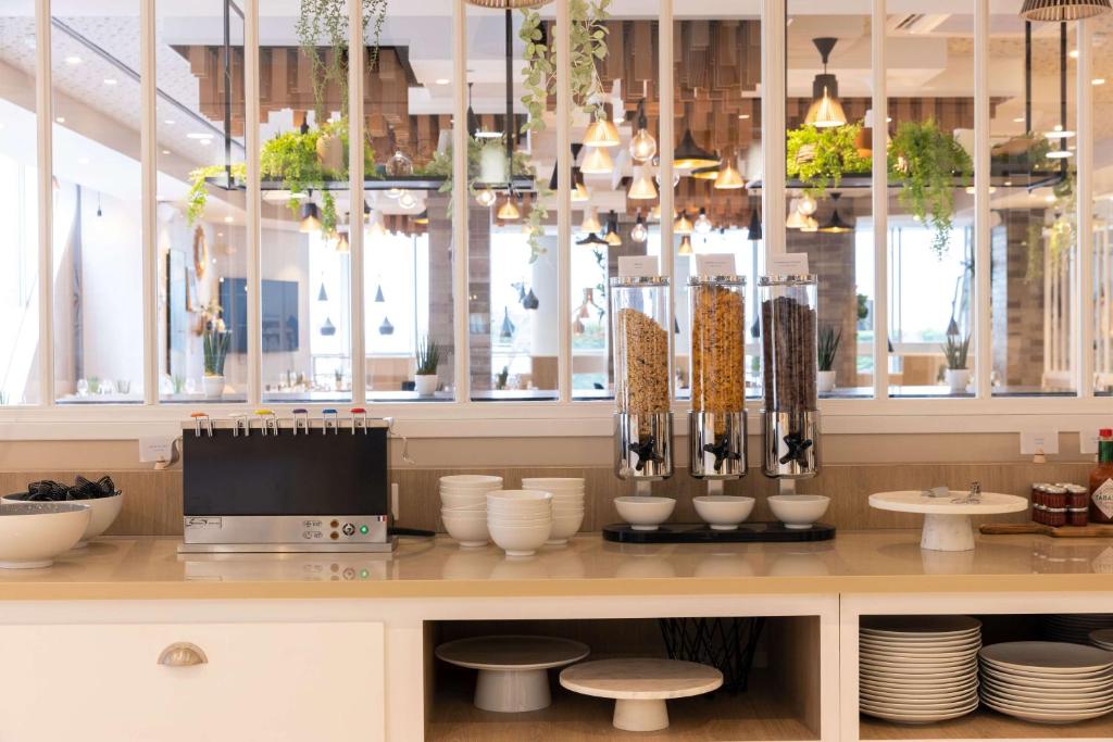 um restaurante com um balcão com pratos e vasos em Hilton Garden Inn Le Havre Centre em Le Havre
