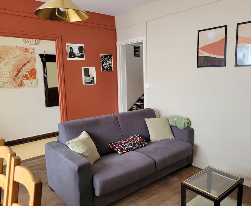 salon z fioletową kanapą z poduszkami w obiekcie Gîte Moussette - Bord de Mer - 4/6 pers. w mieście Quinéville