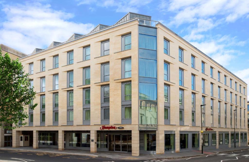 a large building with glass windows on a street at Hampton By Hilton Bath City in Bath